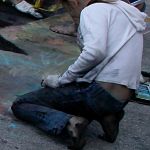 Barefoot street chalk artist with dirty legs & feet